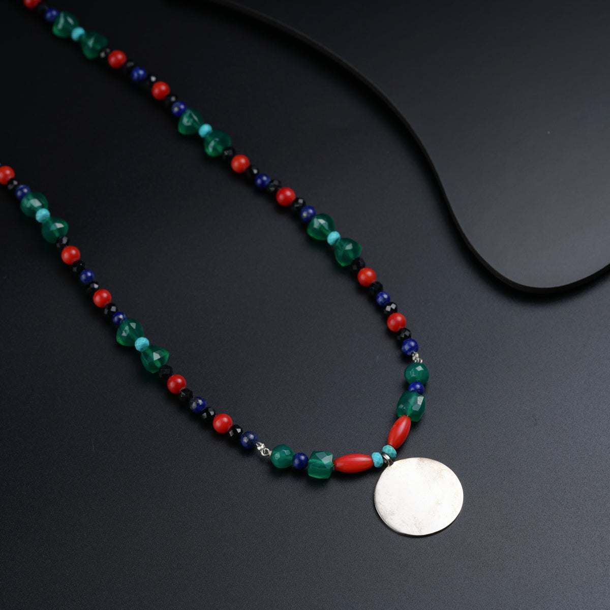 a necklace with a disc on a black surface