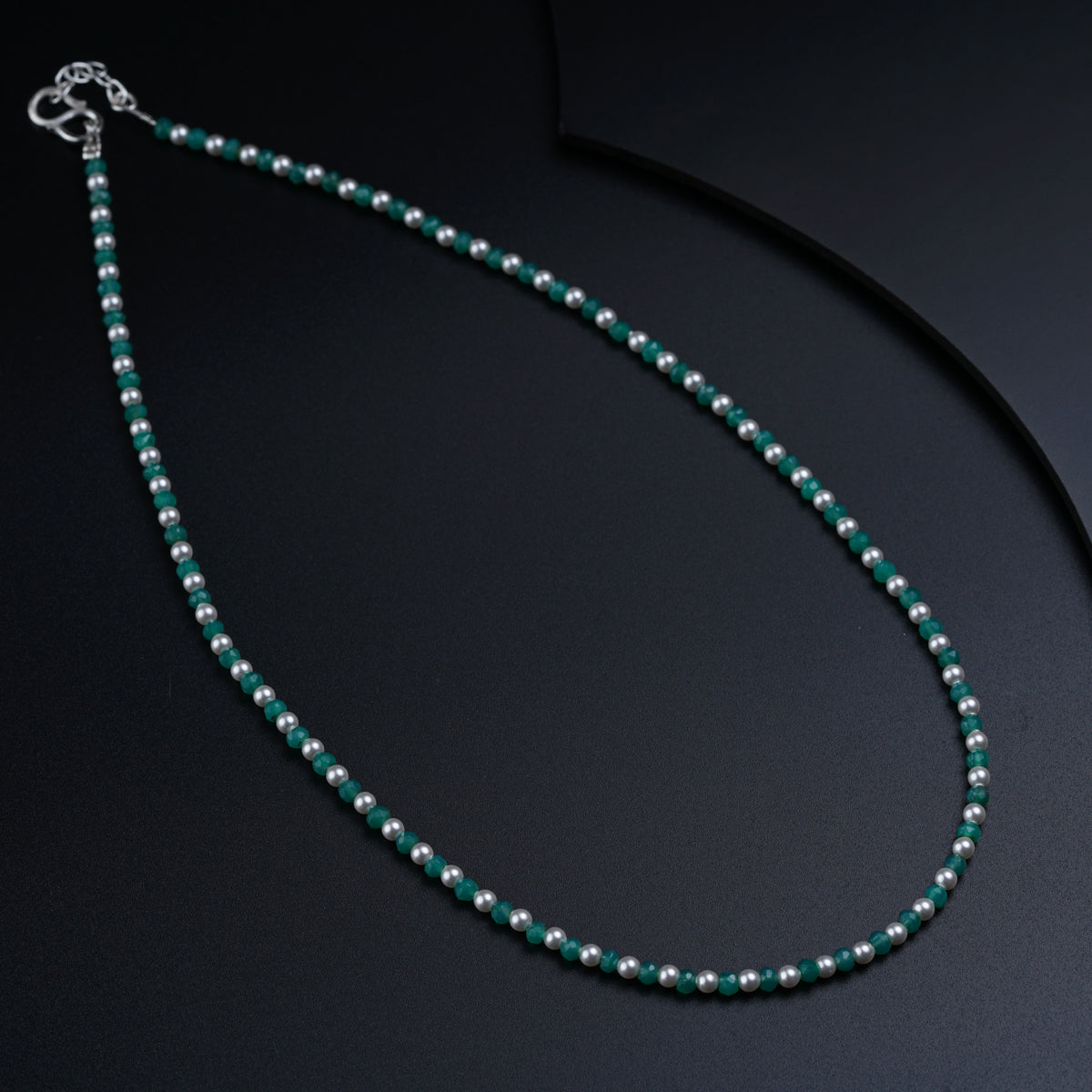 a beaded necklace with a clasp on a black surface