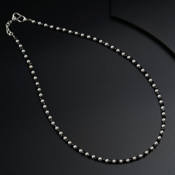 a silver beaded necklace on a black surface