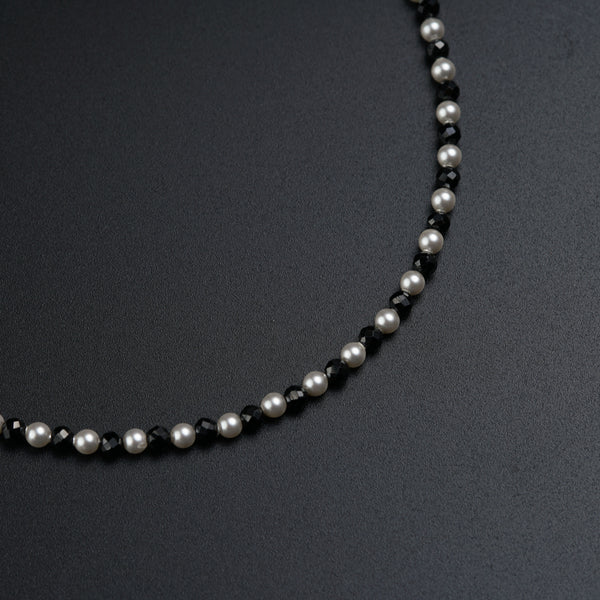 a black and white beaded necklace on a black surface