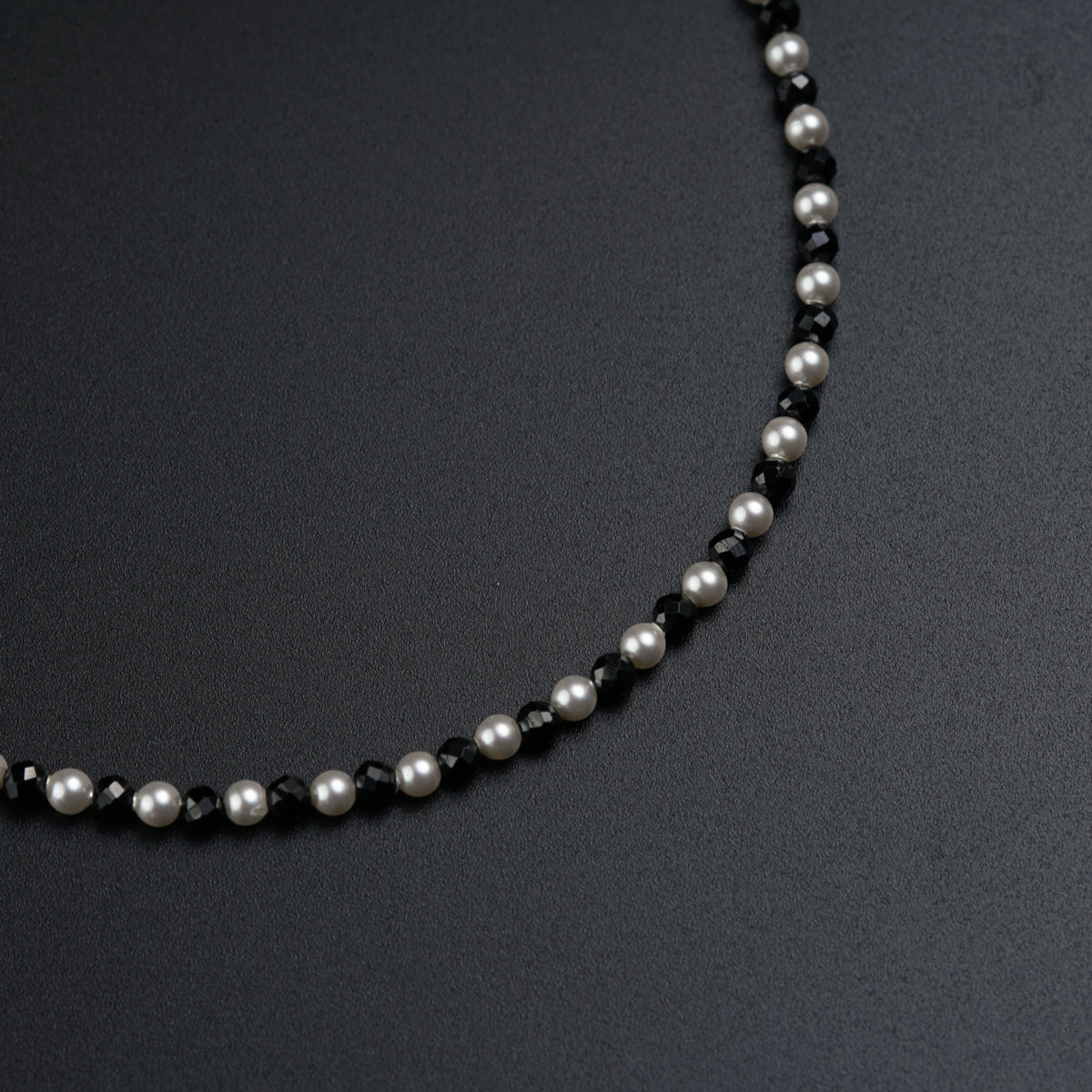 a black and white beaded necklace on a black surface