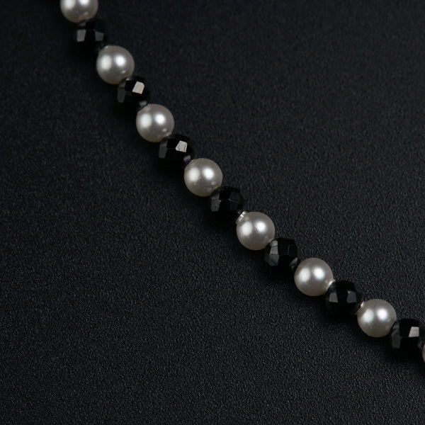 a black and white beaded necklace on a black surface