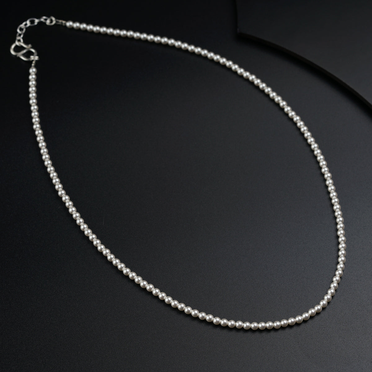 a white beaded necklace on a black surface