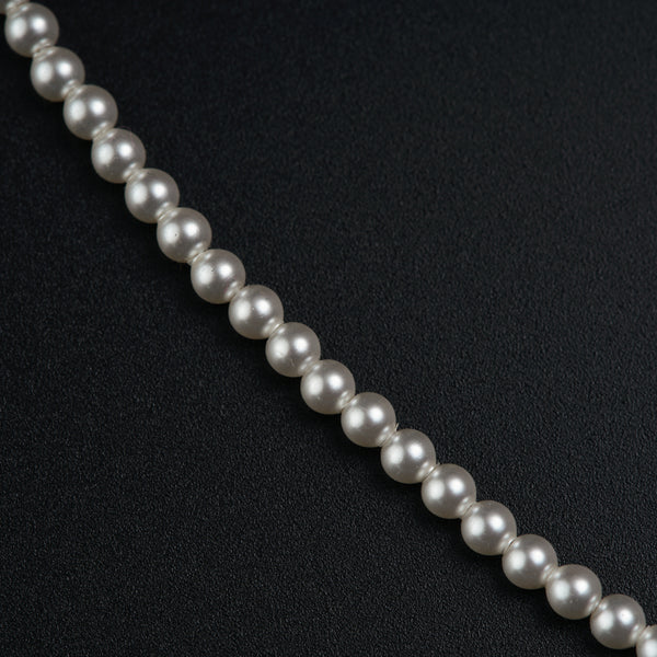 a long strand of white pearls on a black surface