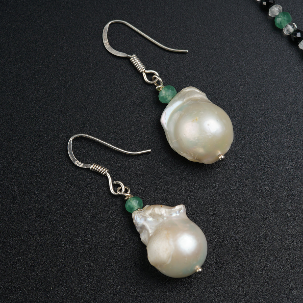 a pair of earrings with pearls and green beads