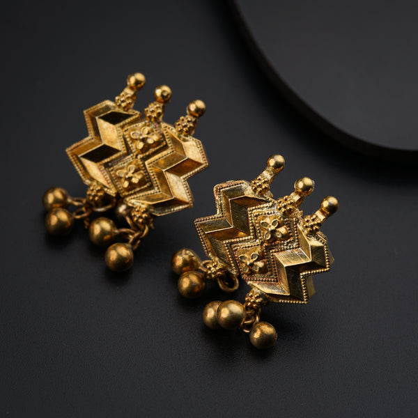 a pair of gold earrings on a black surface