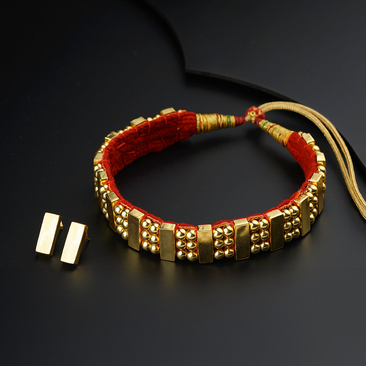 a red and gold beaded bracelet and a pair of earrings