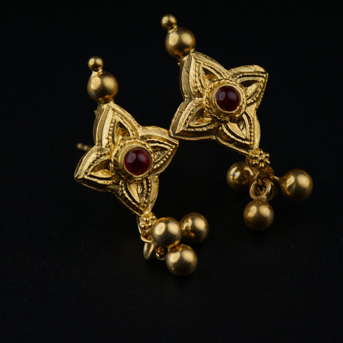 a pair of gold earrings with red stones