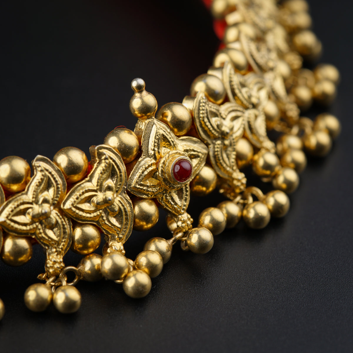 a close up of a gold necklace on a black surface