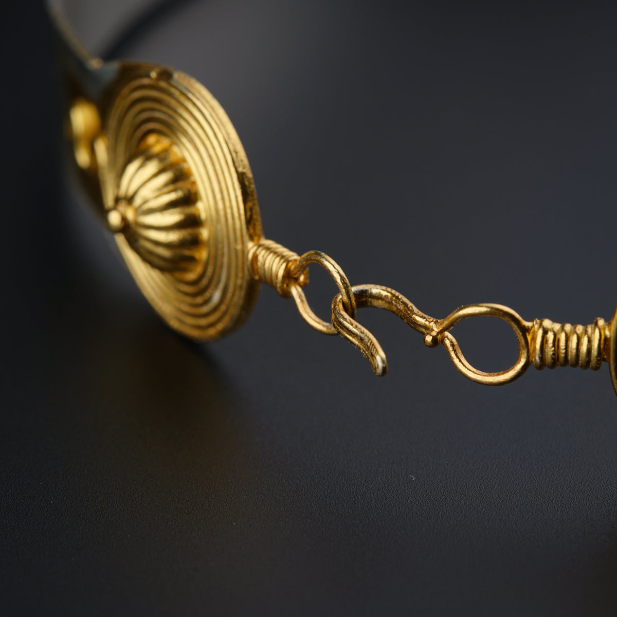 a close up of a gold necklace on a black surface