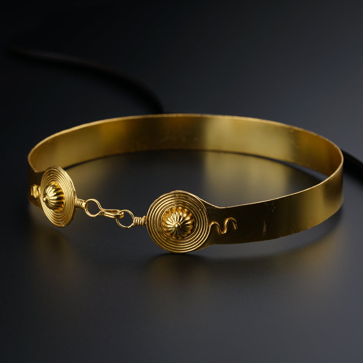 a close up of a gold bracelet on a black surface