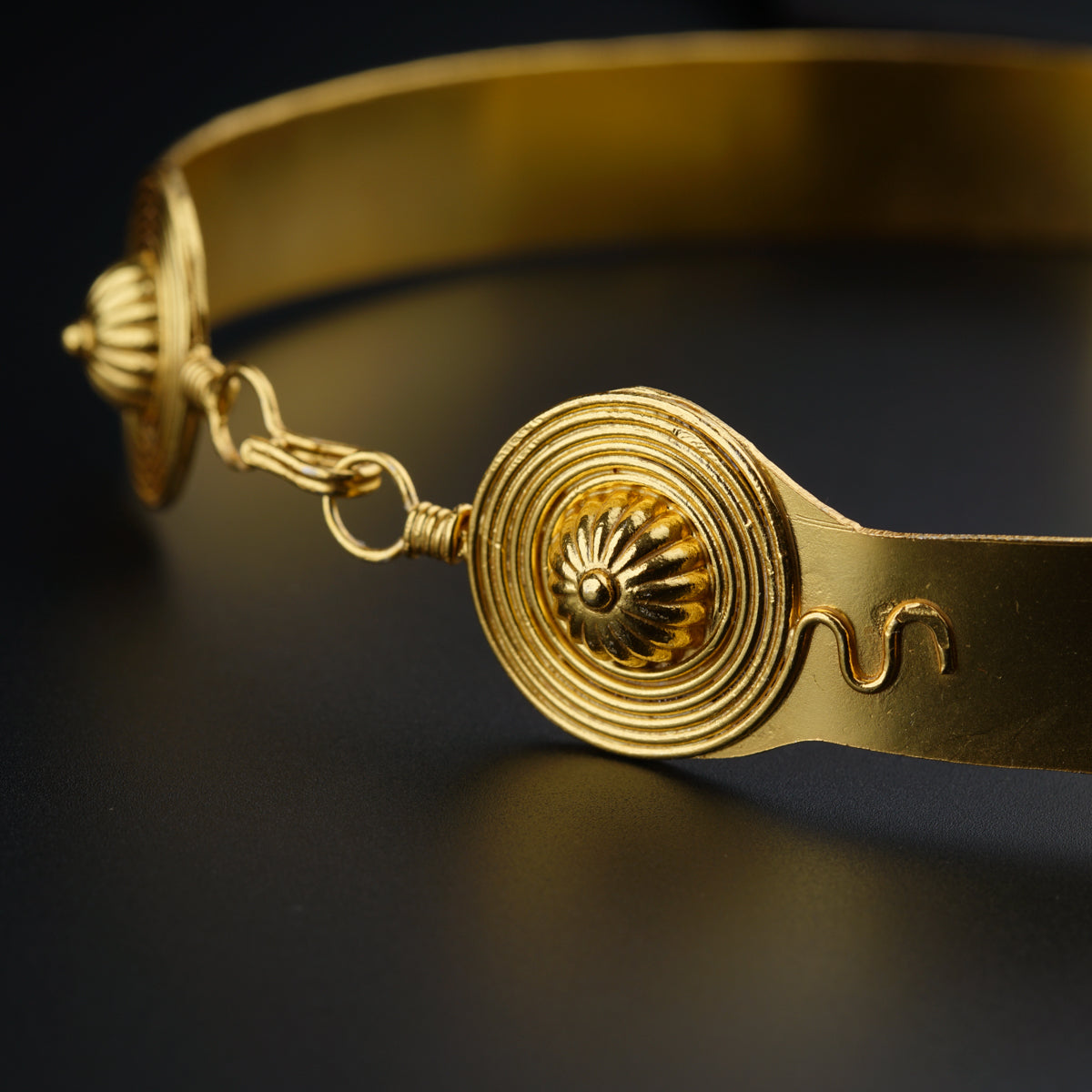 a close up of a gold bracelet on a black surface