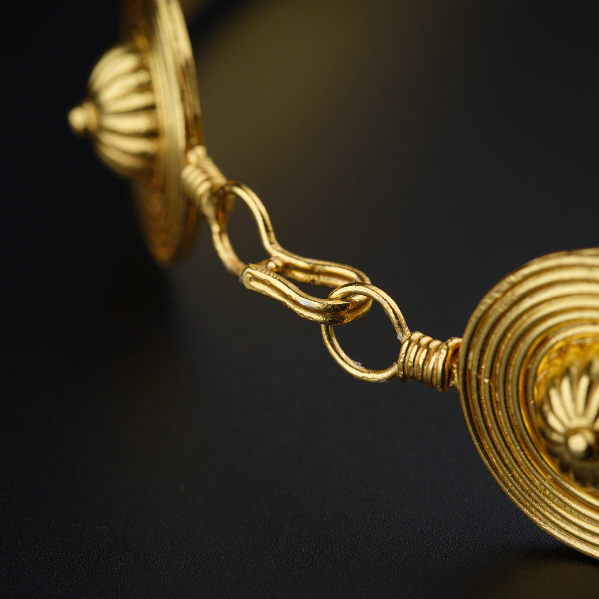 a close up of a gold necklace on a black surface