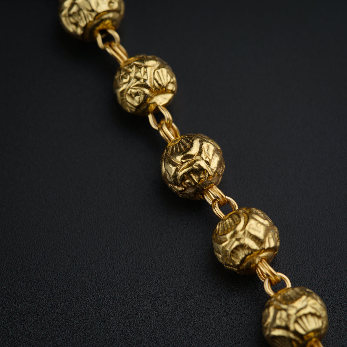 a close up of a gold bracelet on a black surface