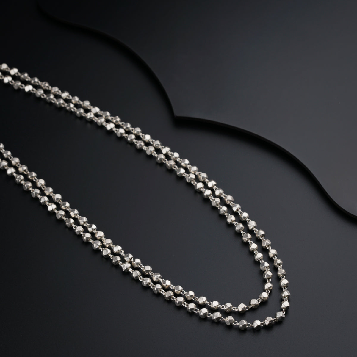 a silver chain with a diamond clasp on a black surface