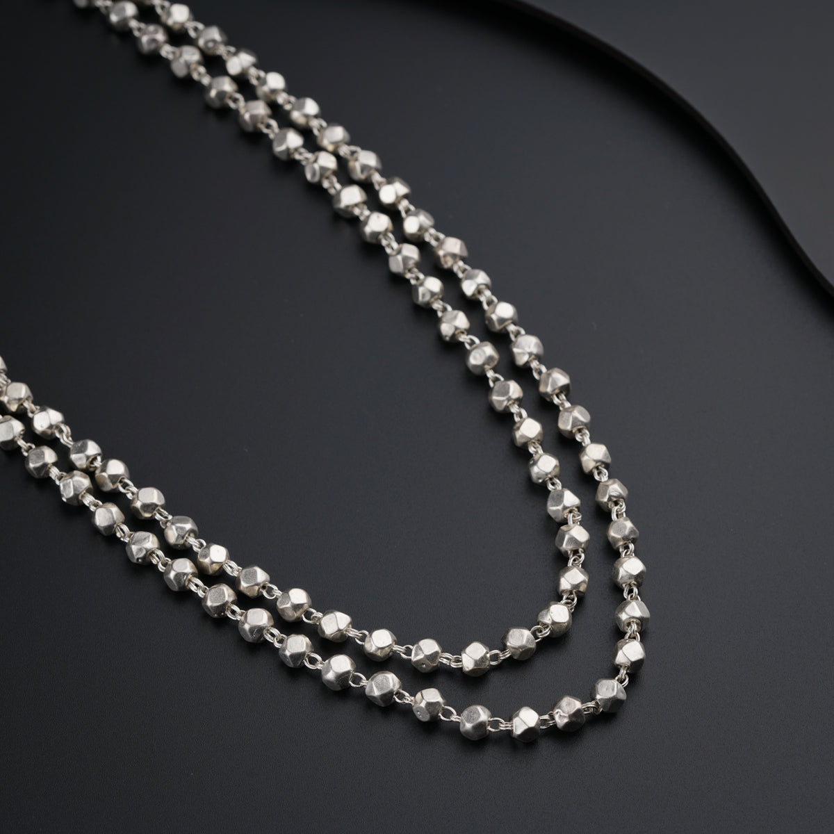a long silver chain on a black surface