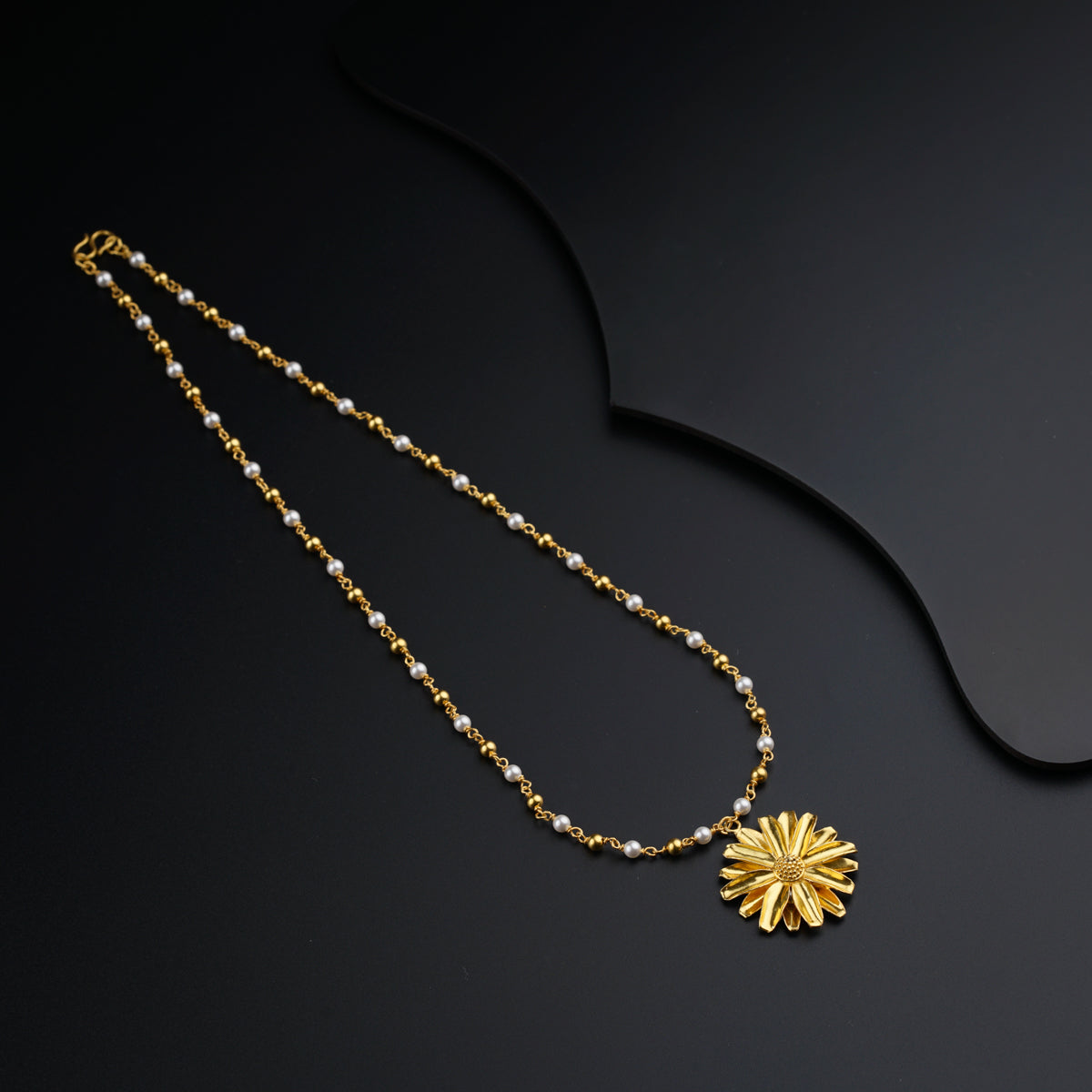 a necklace with a flower on a black background