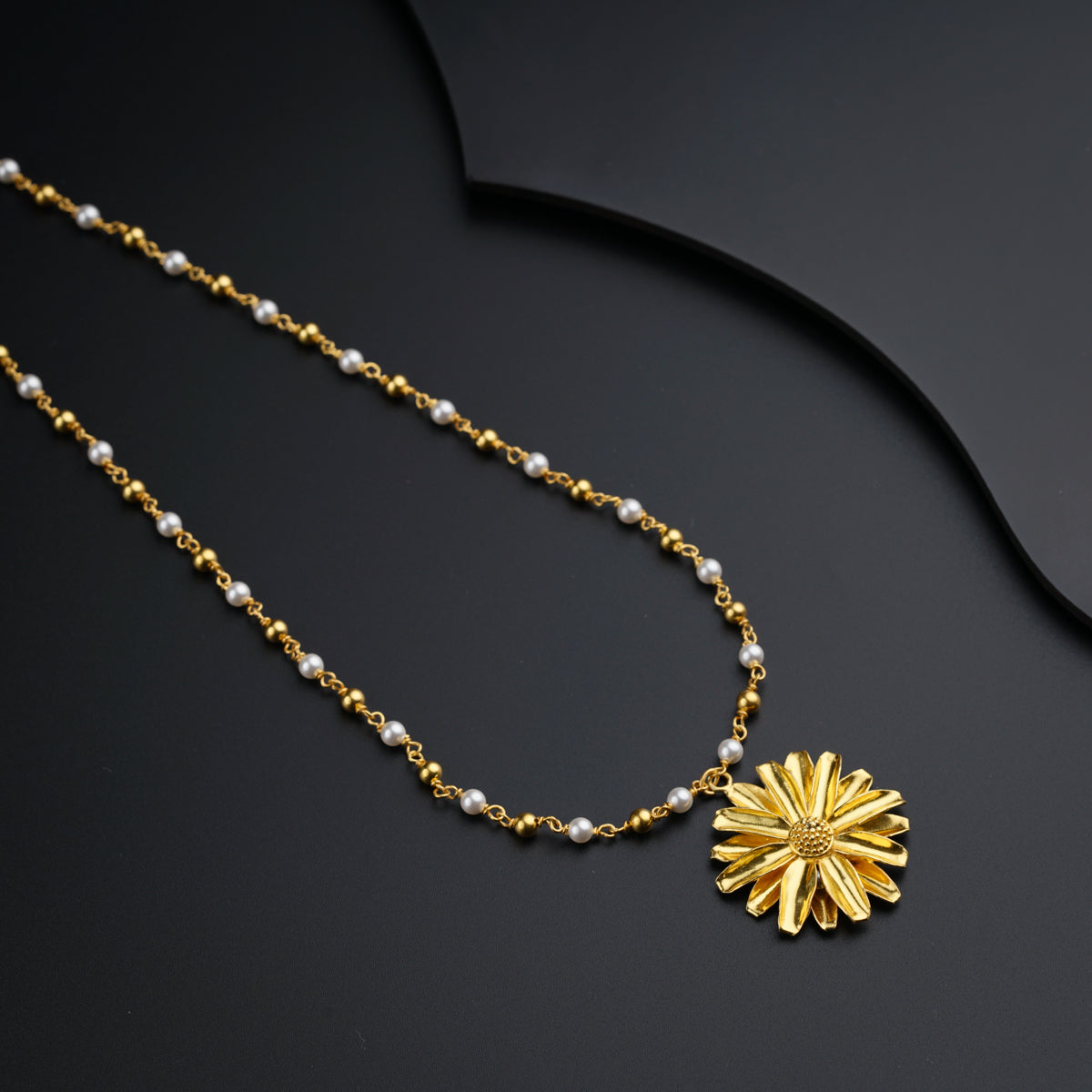 a necklace with a flower on a black surface