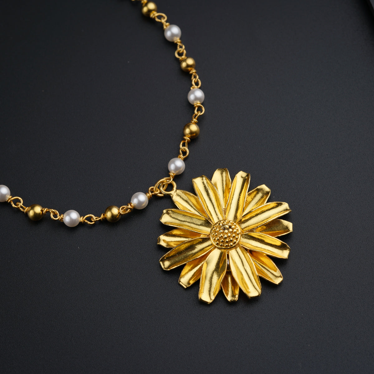 a gold necklace with a flower and pearls
