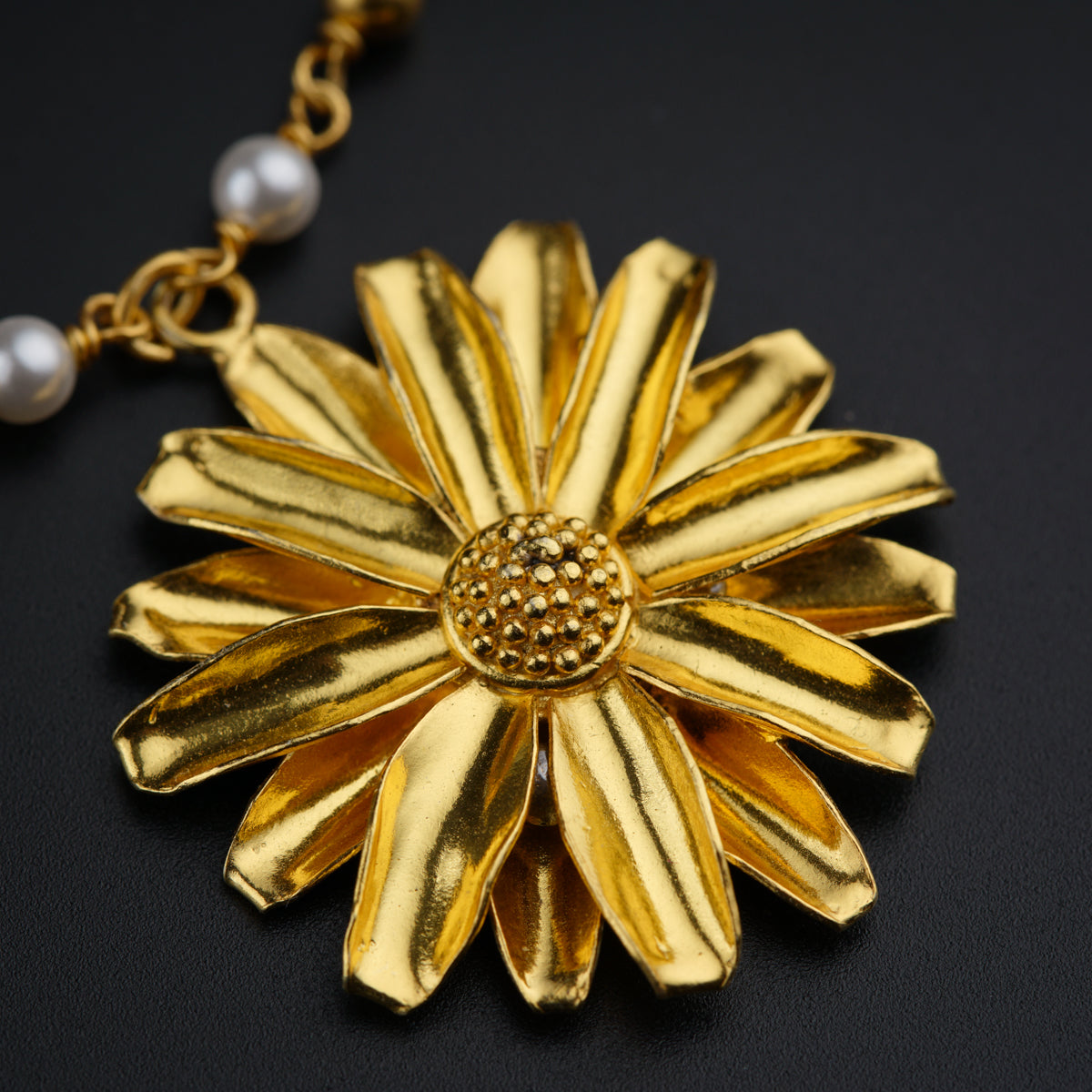 a gold necklace with a flower and pearls