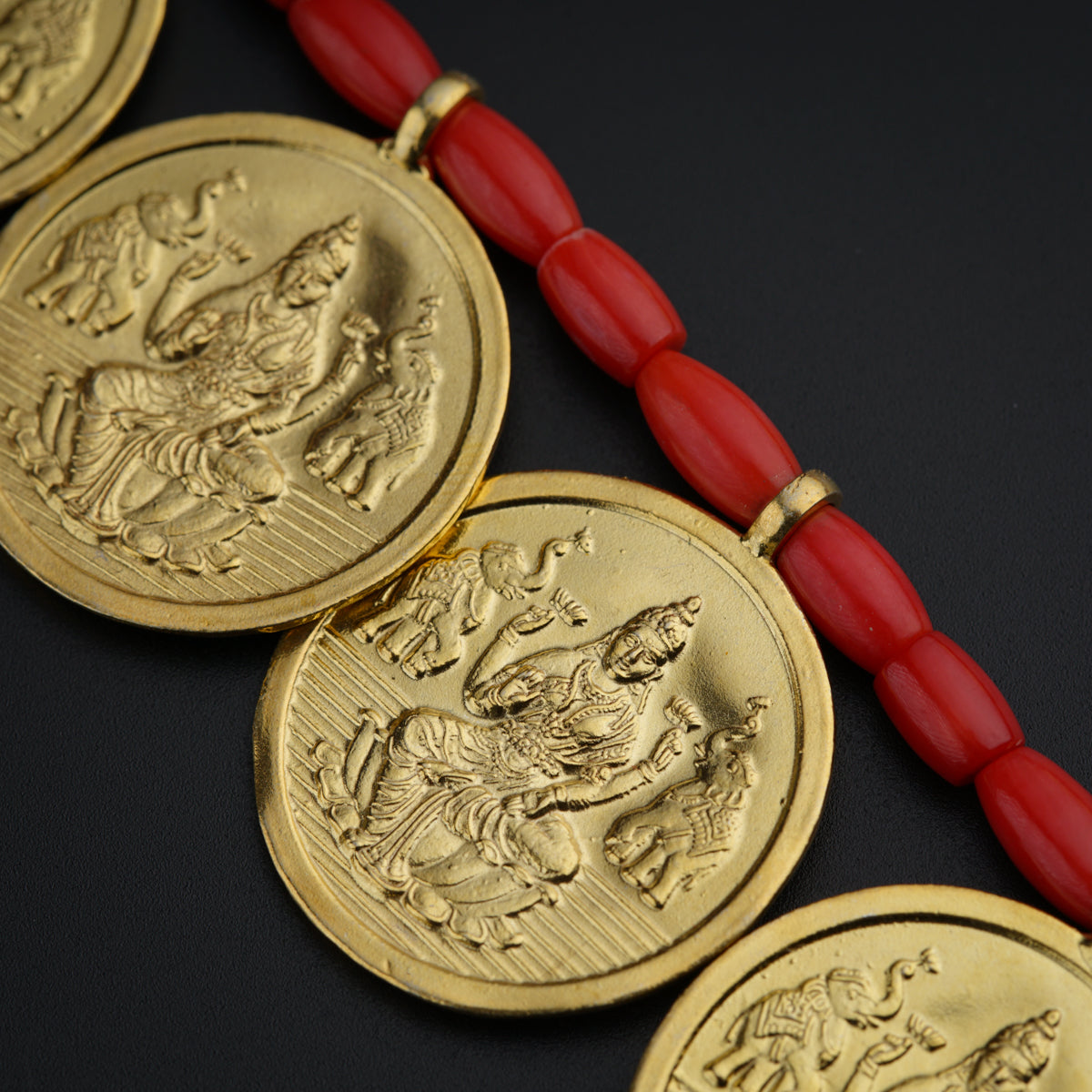 a red beaded necklace with three gold medallions