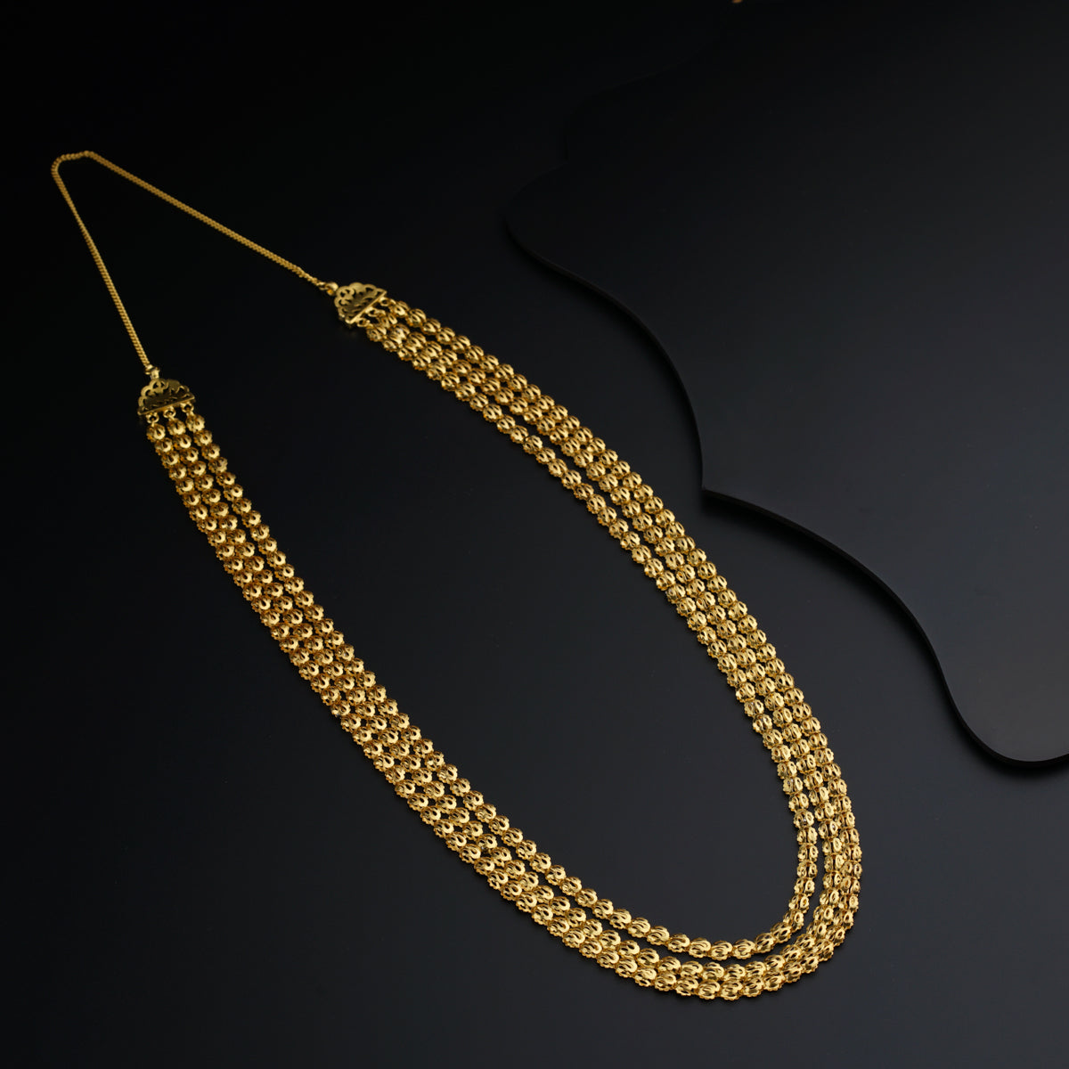 a pair of gold necklaces on a black surface