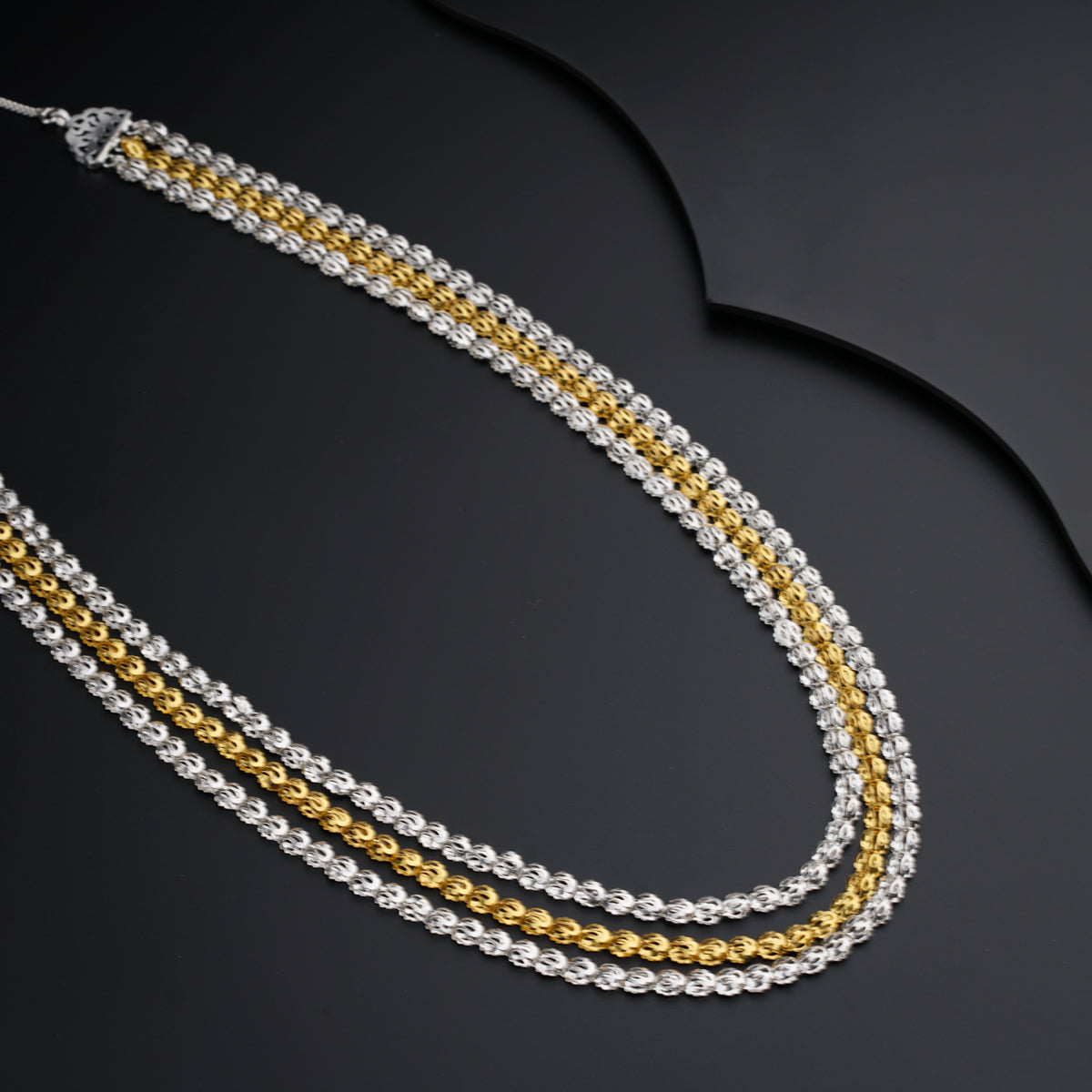 two tone gold and silver necklaces on a black background