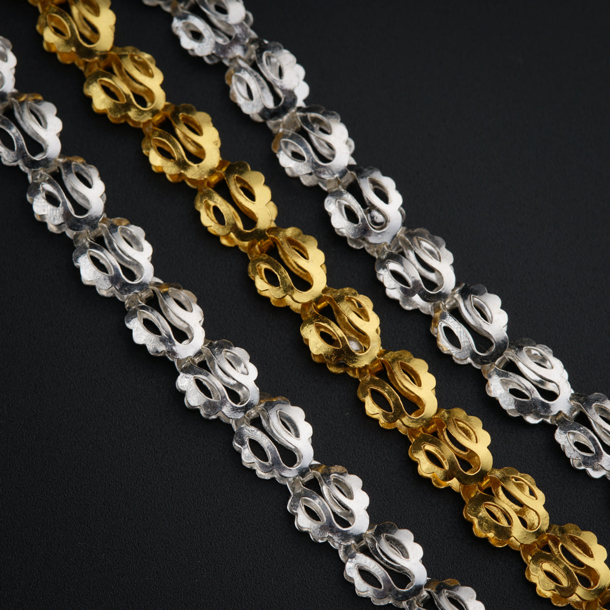 a close up of a chain of gold, silver, and black beads
