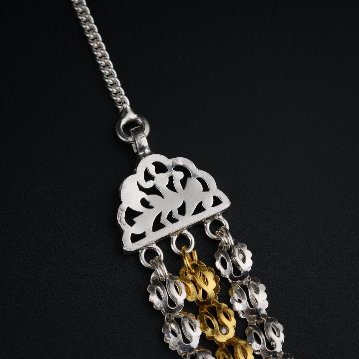 a silver and gold necklace on a black background