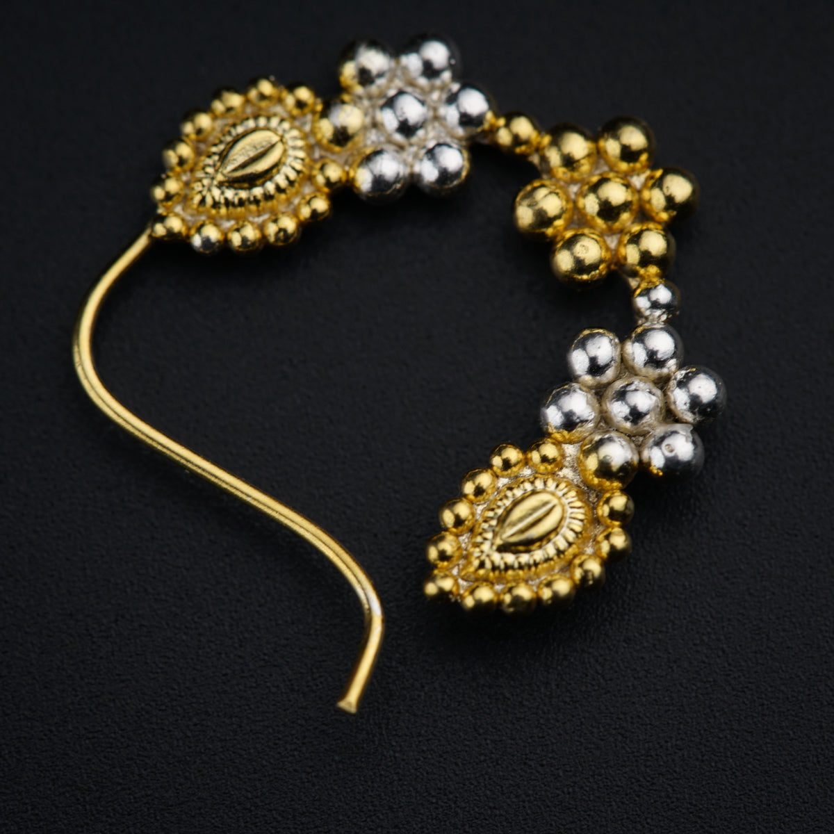 a pair of gold and silver earrings on a black surface