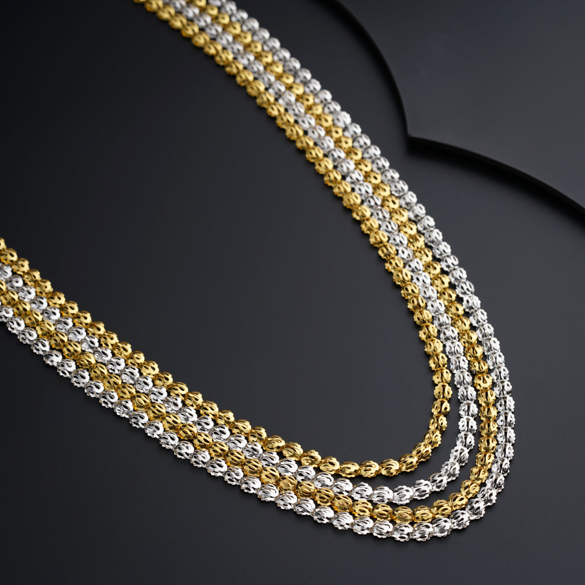 a gold and silver chain on a black surface