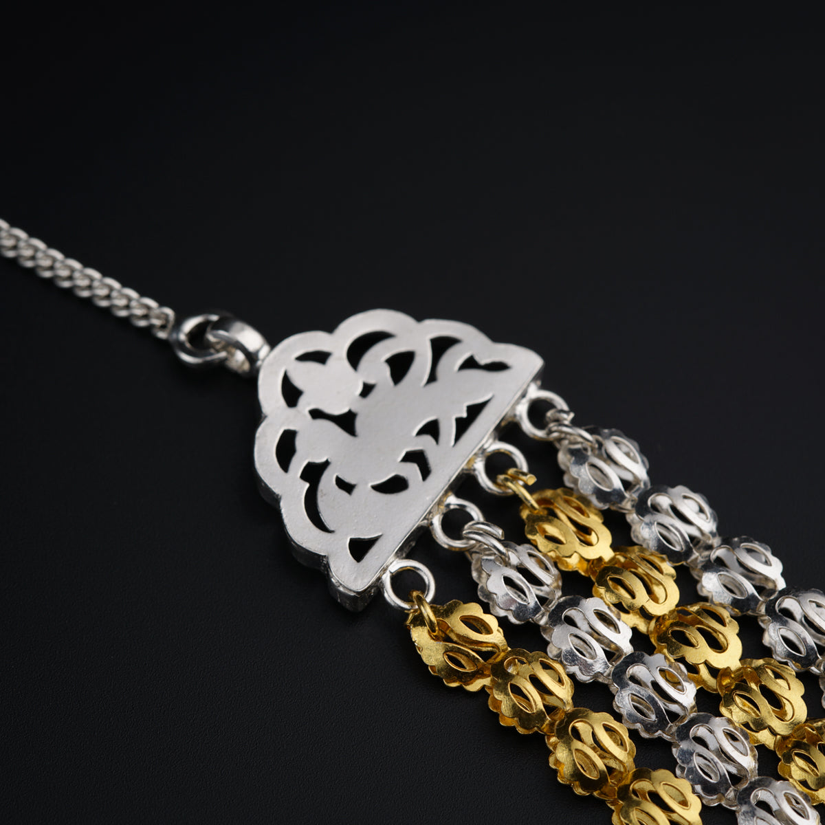 a silver and gold necklace on a black surface