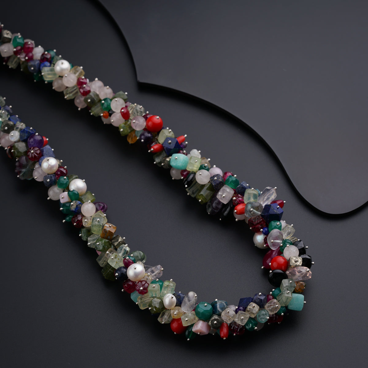 a multicolored beaded necklace on a black surface