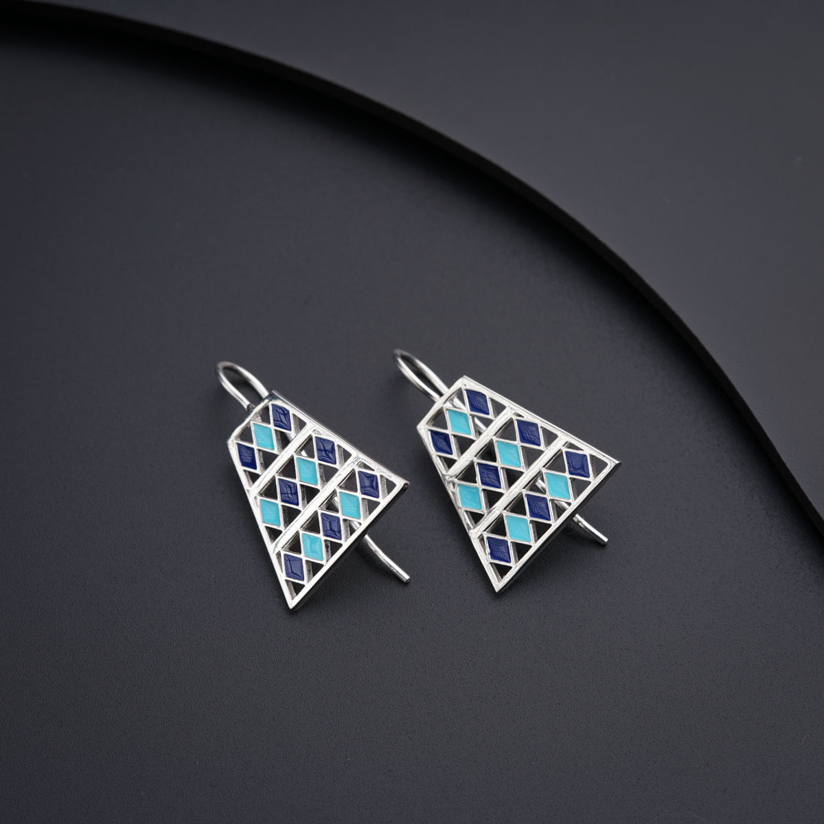 a pair of triangle shaped earrings sitting on top of a table
