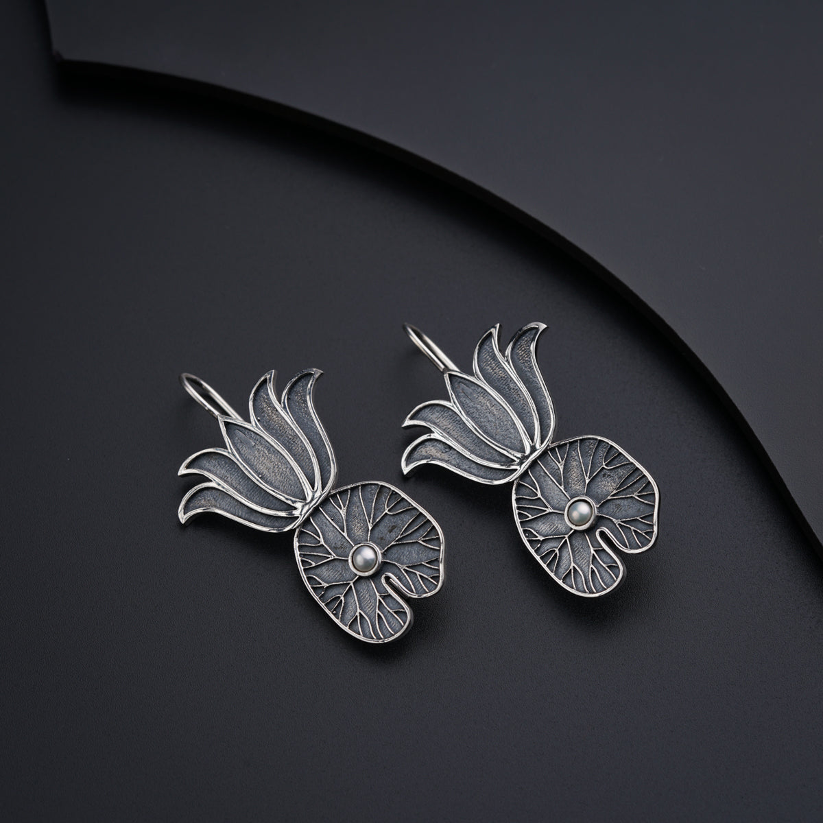 a pair of silver earrings with a flower design