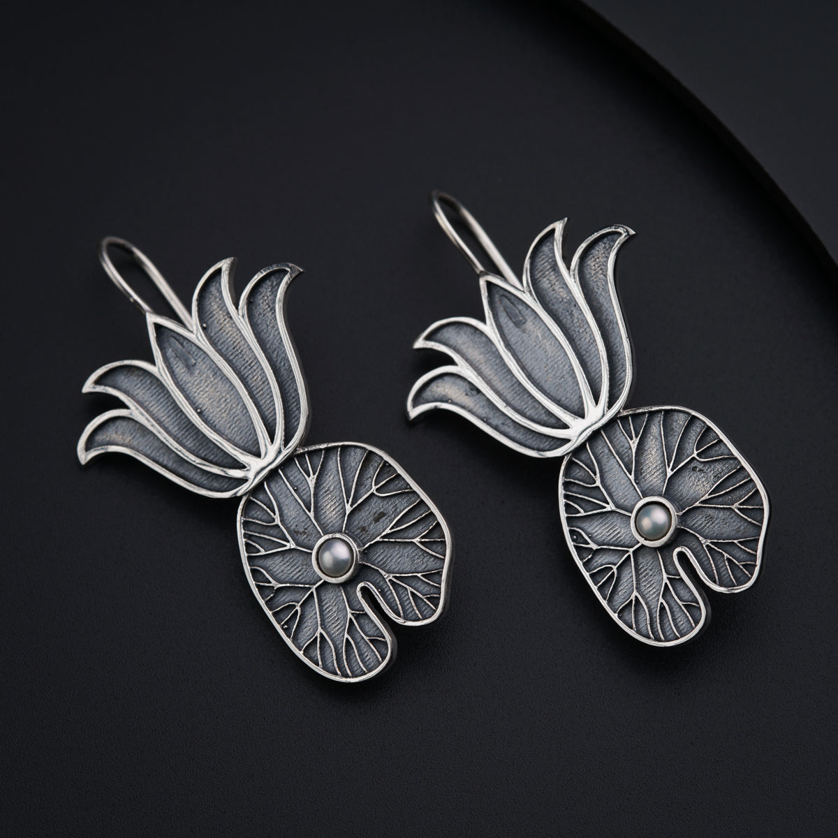 a close up of two silver brooches on a black surface