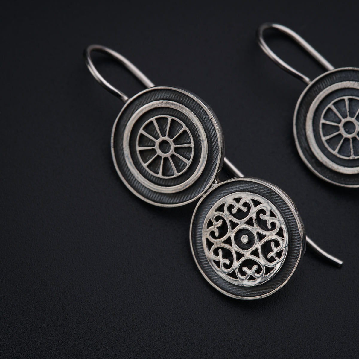 a pair of silver earrings on a black background