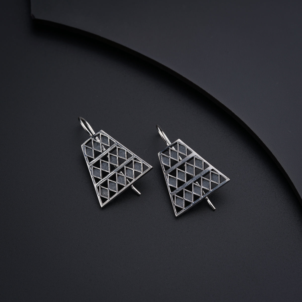 a pair of triangle shaped earrings on a black surface