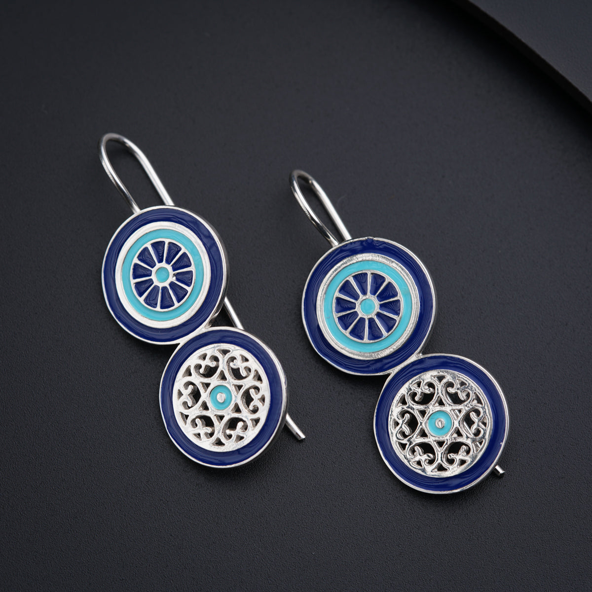 a pair of blue and white earrings on a black surface
