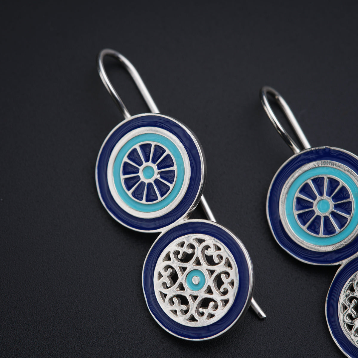 a pair of blue and white earrings on a black surface
