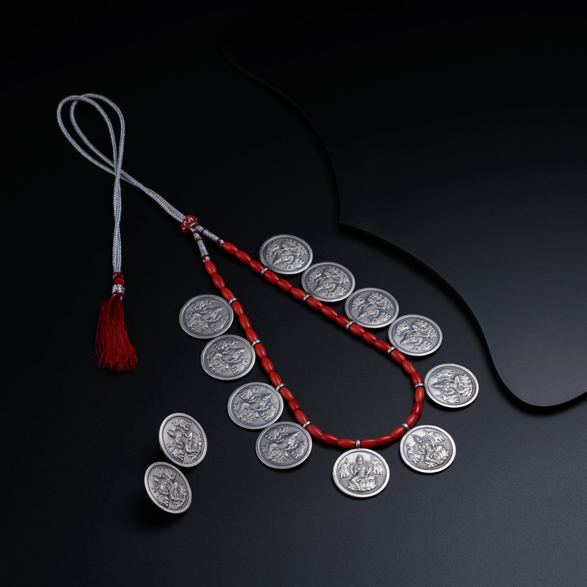 a red string with a coin and a tassel