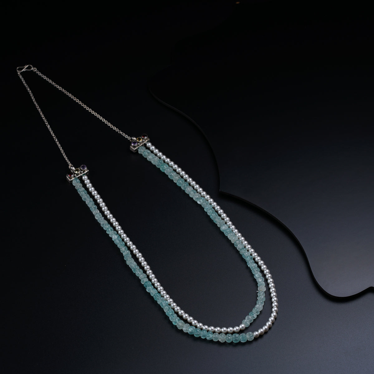 a long necklace with beads on a black surface