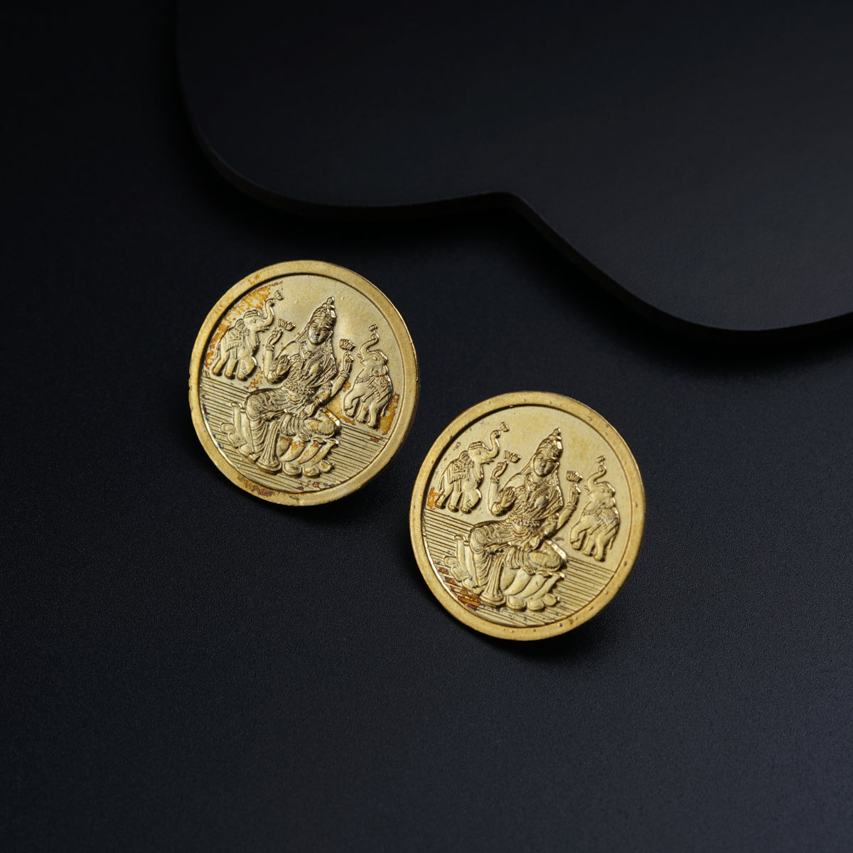 a pair of gold coins sitting on top of a black surface