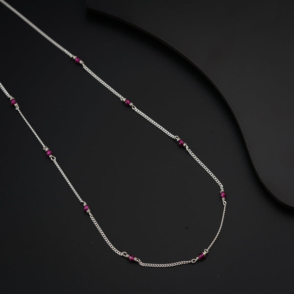 a silver chain with a red bead on it