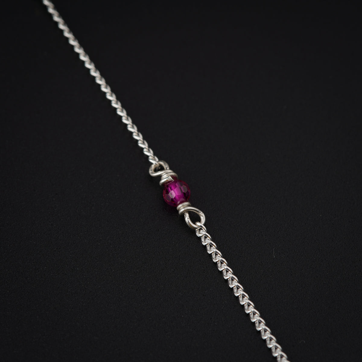 a silver chain with a purple bead on it