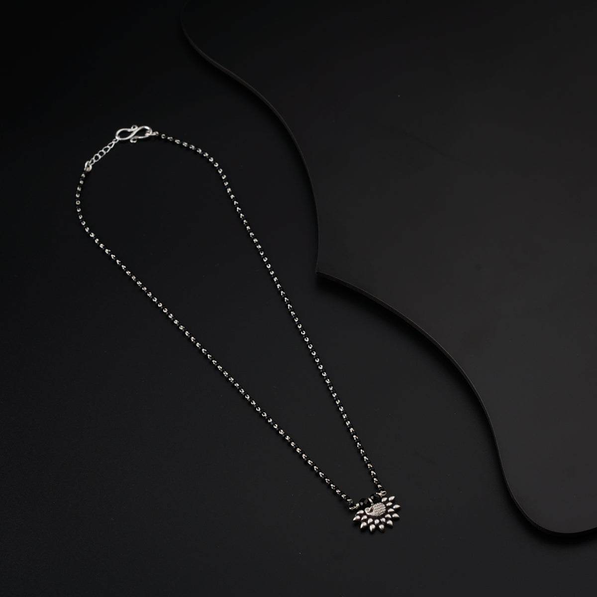 a necklace on a black surface with a chain