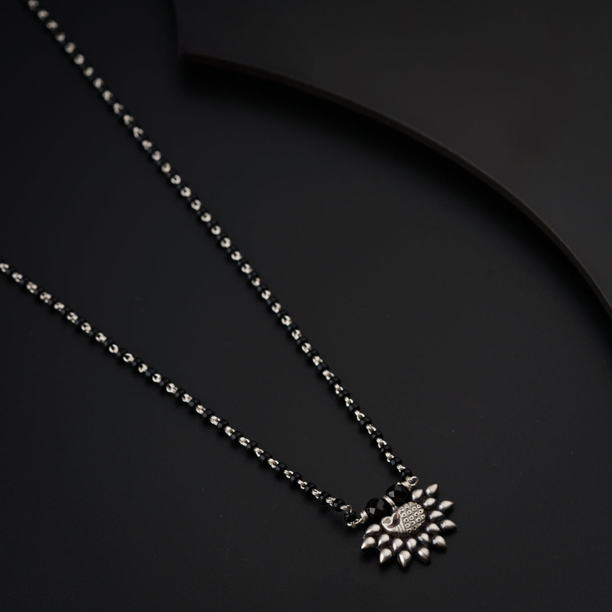 a necklace with a flower on a black background