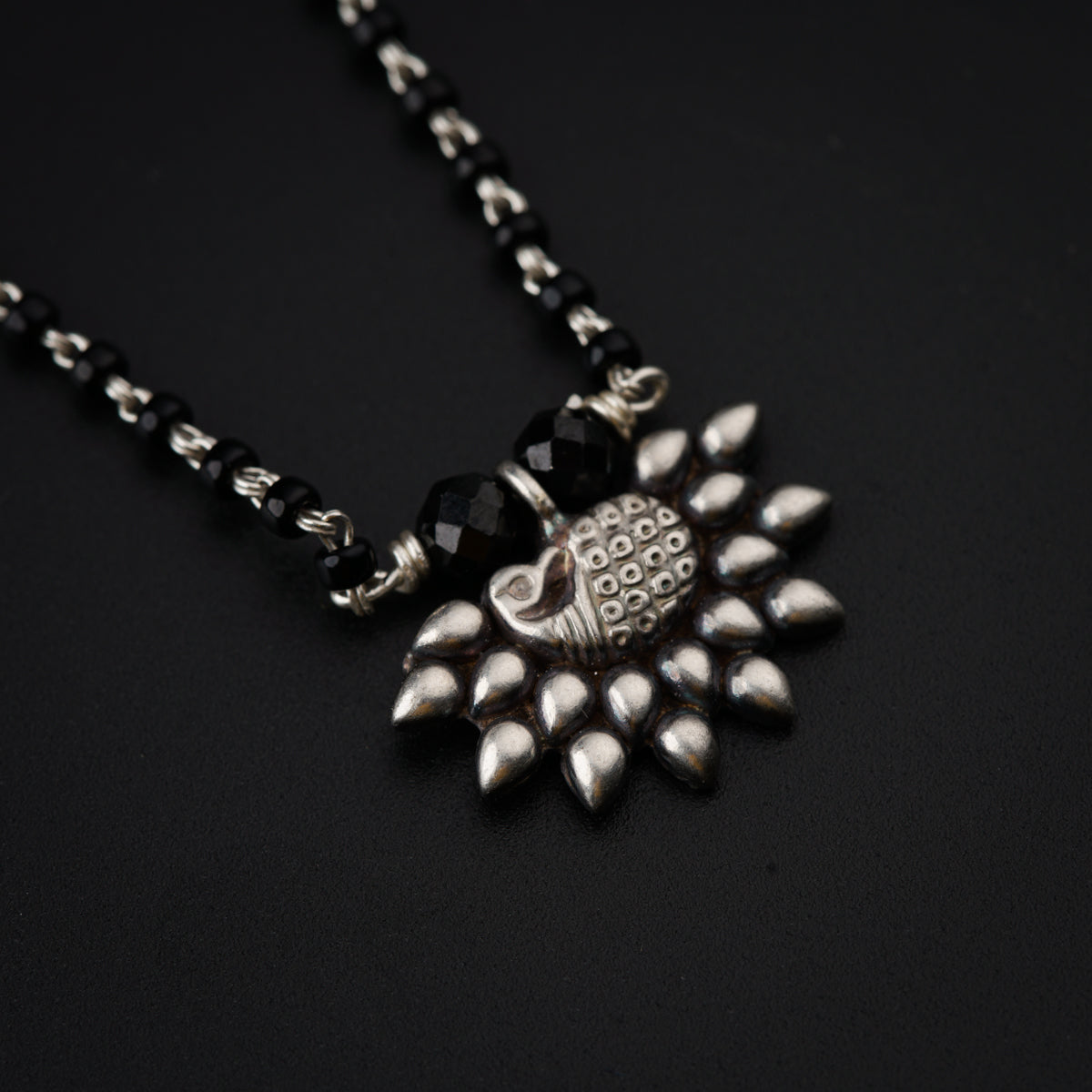 a black and silver necklace on a black surface