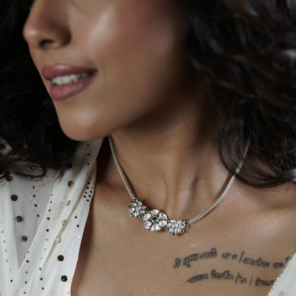Woman wearing silver necklace and earrings with green stones