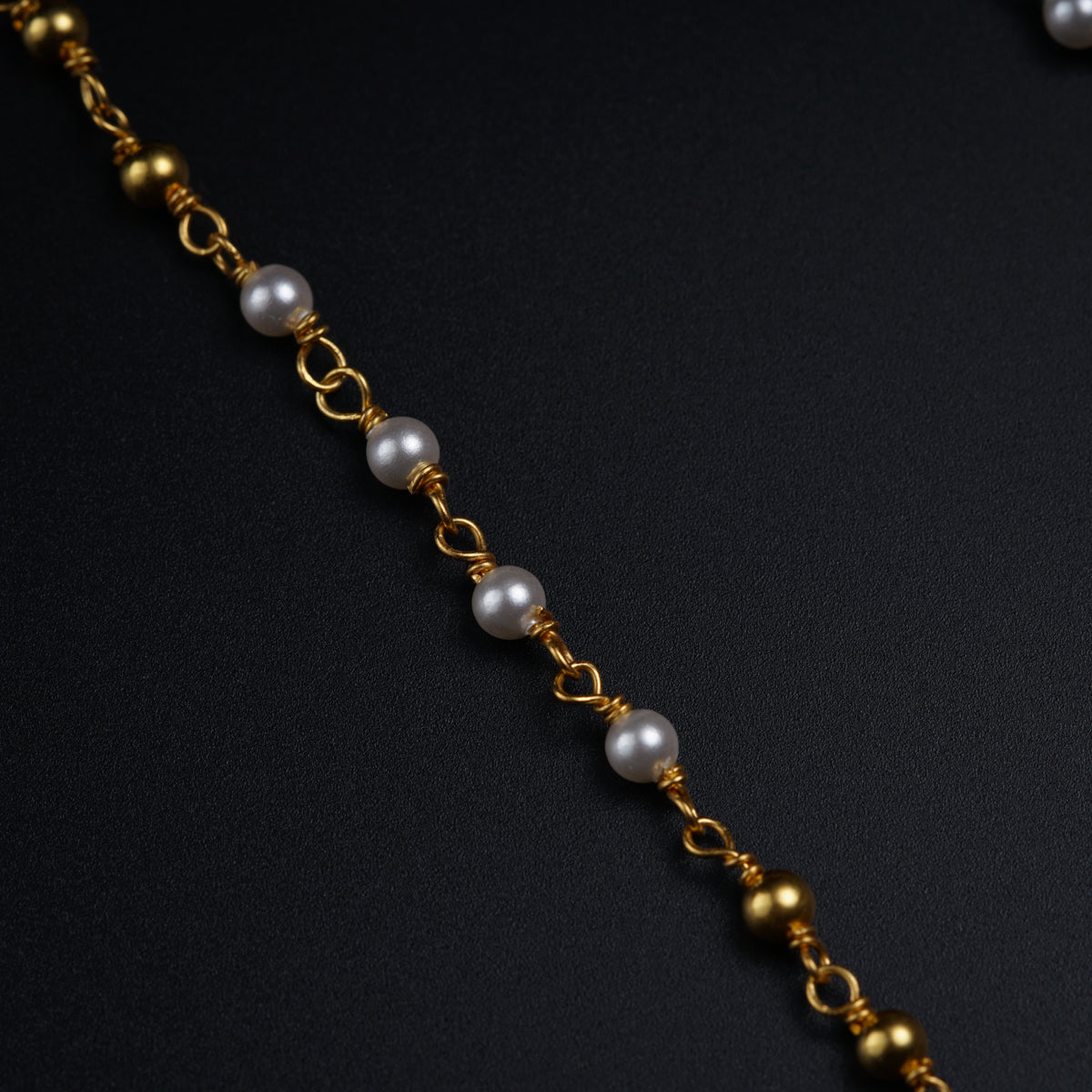 a close up of a chain with pearls on it
